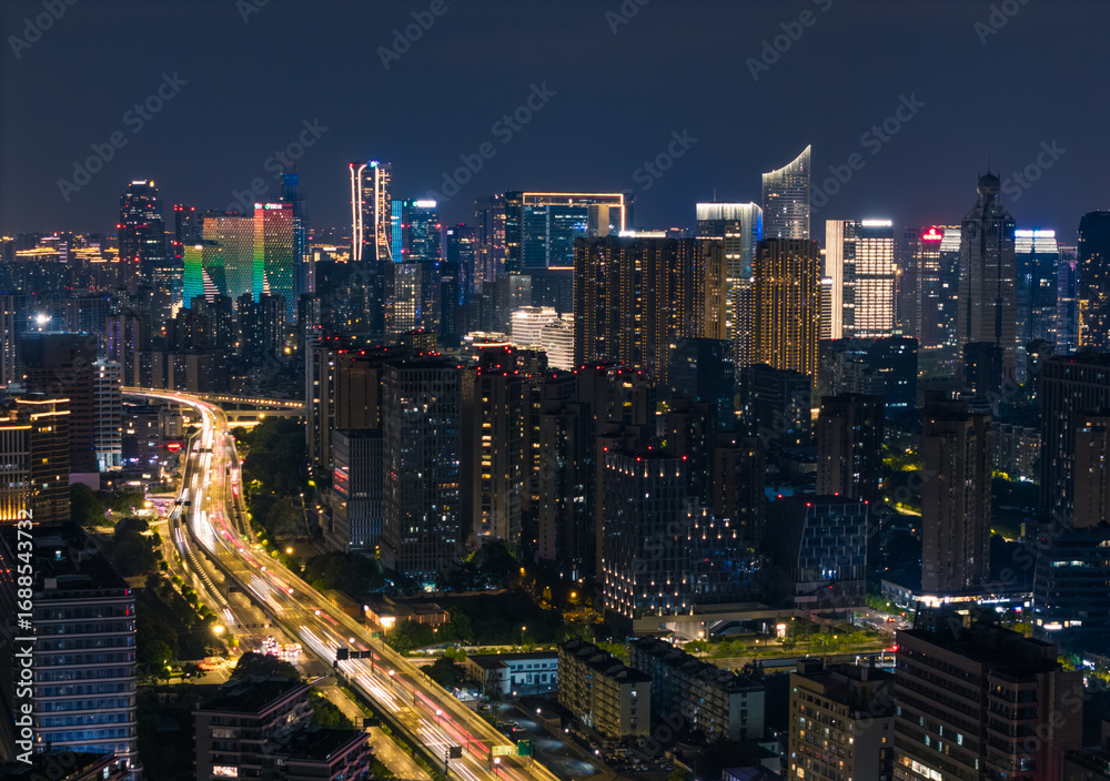Fototapeta premium Hangzhou cityscape displays illuminated skyscrapers and a busy highway during the evening hours