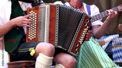 oktoberfest: Traditional Bavarian musicians playing accordion and guitar outdoors.