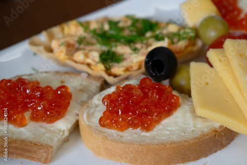 Sandwiches with red caviar, cheese and olives on a plate 