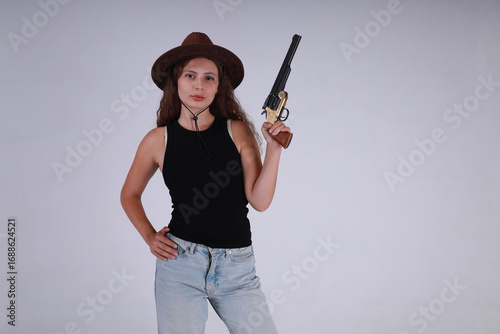 Young woman in hat holding vintage black powder revolver on gray background