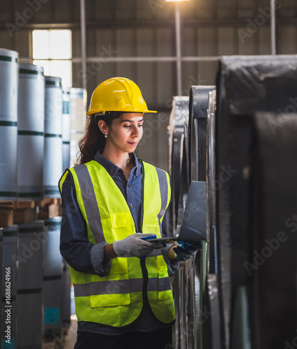 Industrial worker inspection warehouse in safety helmets and high-visibility vest glove use laptop inspect roll material in industrial. image highlight safety technology modern industrial operation.