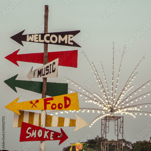 Colorful directional signs at an outdoor festival or event.