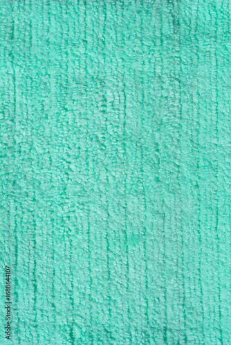 A vertical close-up shot of a light green microfiber cloth with a fluffy texture, serving as a clean and simple background.
