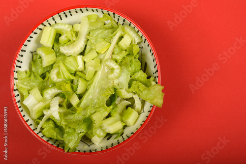 Quadro em tela A vibrant, high-angle view shows a bowl of fresh green celery and lettuce salad