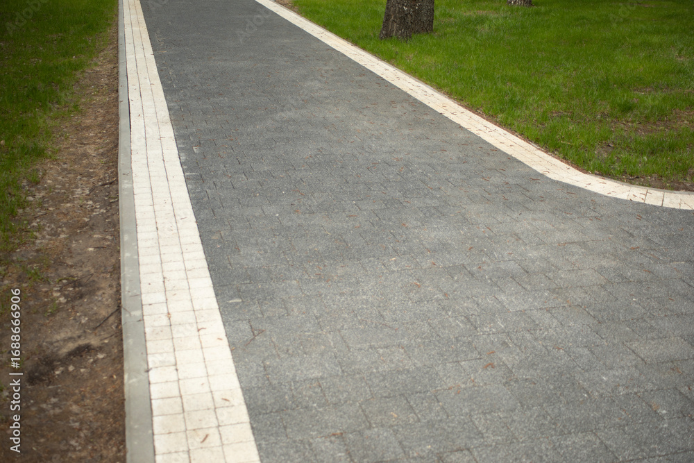 Obraz premium A path in the park. Tile driveway. Empty area.