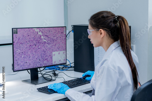 Researcher analyzes tissue sample on computer in laboratory setting during work hours