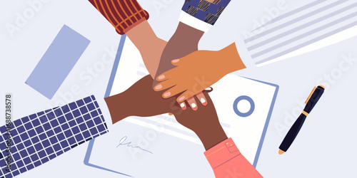 Diverse team of professionals stacking hands together over documents in a business meeting