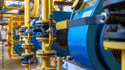 Industrial boiler room with yellow gas pipes and blue boilers