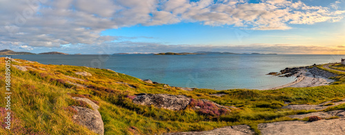 Karibik-Feeling auf South Uist – türkisblaues Panorama in den Äußeren Hebriden, Schottland -Küstenlandschaft mit türkisblauem Wasser, violetter Besenheide und Sandbucht. Sommerliche Ruhe und Fernweh.