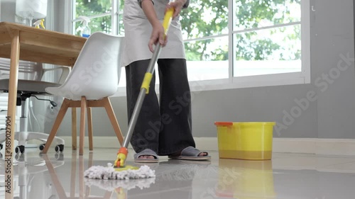 A woman is cleaning the house, cleaning the furniture with a spray and a duster, emphasizing hygiene, order, and responsibility towards the home.