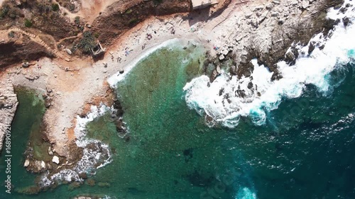 Scenic Top View of Blue Ocean Waves Breaking Against Rocky Coastline
