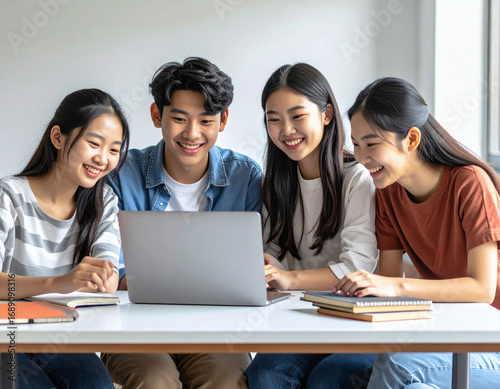 Happy group of young Asian students working together on a laptop, sharing ideas and collaborating on a university project