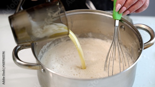 Chef whisking ingredients in stainless steel pot