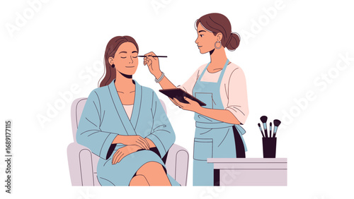 Professional makeup artist applying eyeshadow to a seated client wearing a spa robe in a bright studio setting