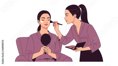Professional makeup artist applying blush to a seated woman holding a hand mirror in a salon setting