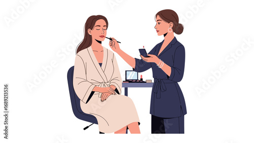 Professional makeup artist applying cosmetics to a seated woman in a robe creating a polished look
