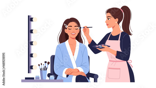 Professional makeup artist applying eye shadow to a happy client in a brightly lit vanity area
