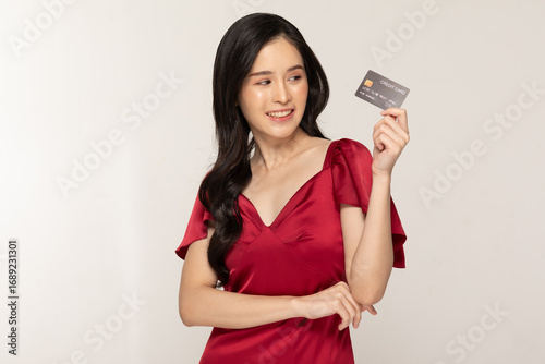 Asian Young woman holding credit card smiling happily wearing red dress with long black hair on white background