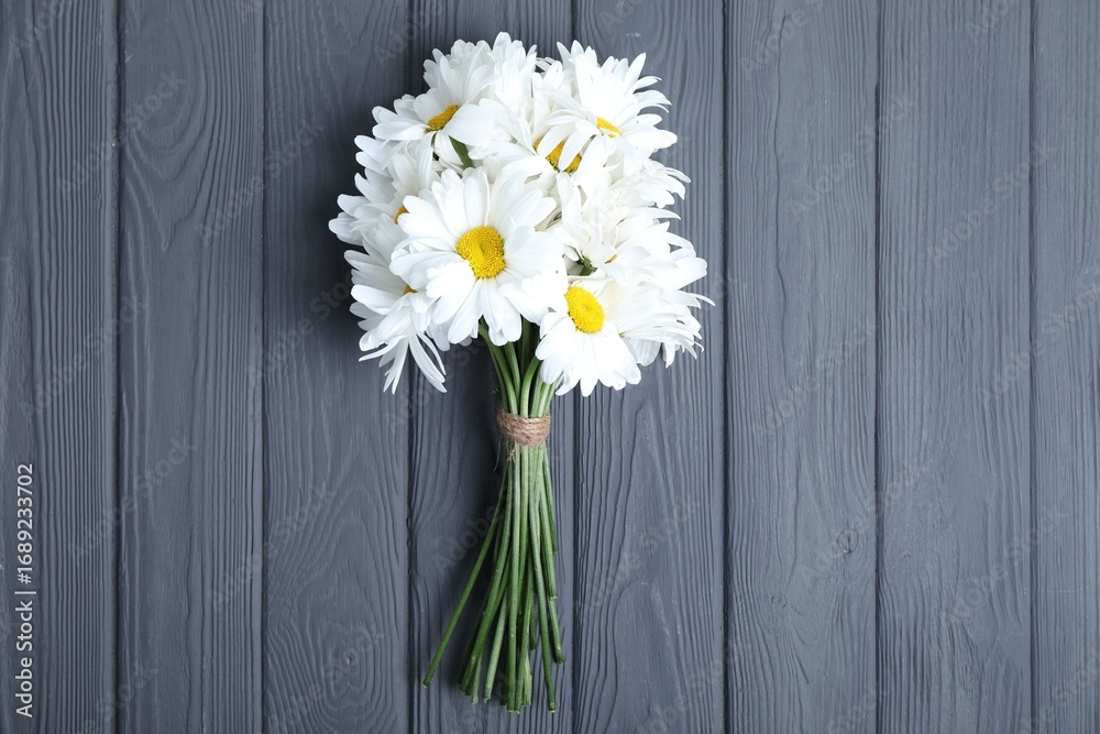 Obraz premium Bouquet of beautiful chamomile flowers on grey wooden table, top view