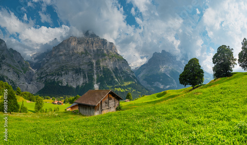 Canvas Print Majestic mountains rise in the background as quaint wooden cabins dot green landscape