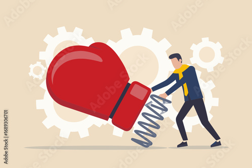 Businessman pushing a giant boxing glove attached to a spring with gears in the background