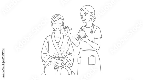 Artist applying makeup to a person wearing a towel wrapped around their head and a robe