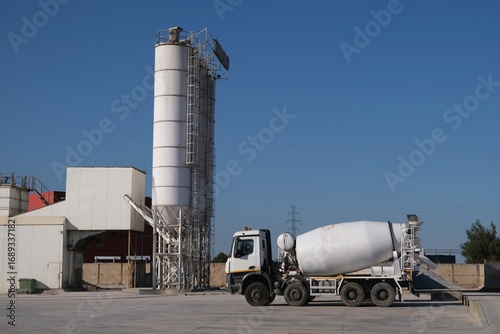 White concrete mixers standing by a modern concrete plant.	