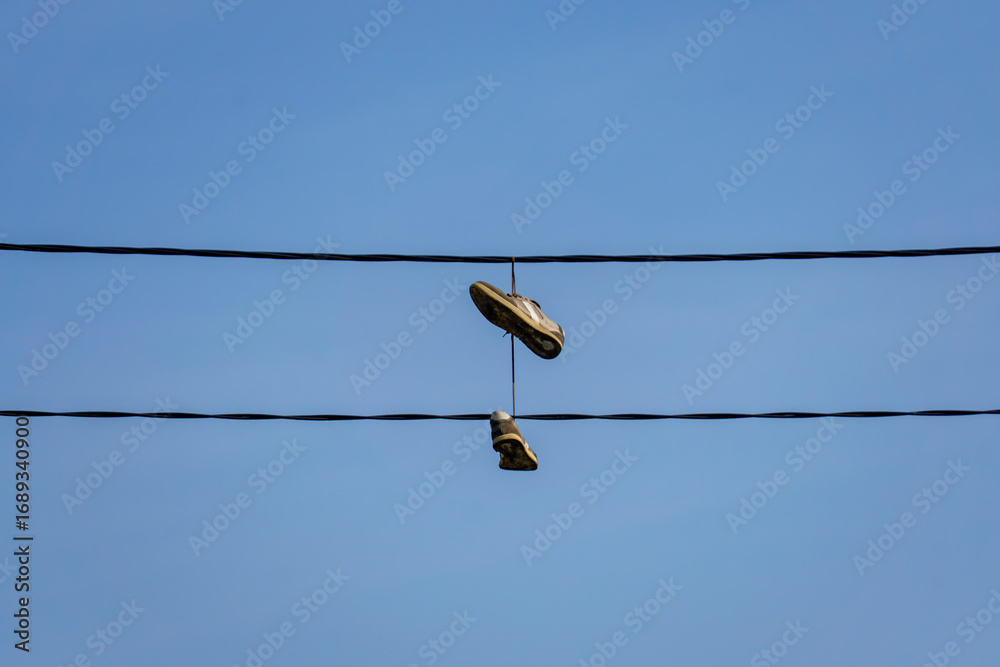 Obraz premium Shoes hanging on power lines against clear sky