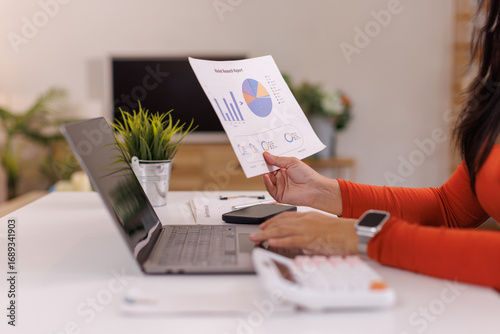 asian woman working on The data analyst business analytics dashboard, utilizing charts and metrics to analyze performance and generate insightful reports for operations management
