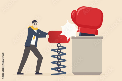 Businessman pushing a spring loaded boxing glove to hit a pop up boxing glove on a box