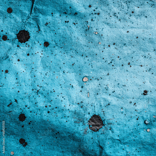 Vintage light blue paper featuring random black ink splatters, crafting grungy artistic texture for graphic design and creative backgrounds