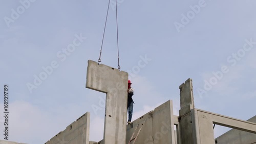 Male workers direct the placement prefabricated concrete slabs for building construction which are lifted crane and assembled according specifications townhouse construction project and work safely.