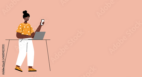 Young Black woman working remotely at a standing desk, using a laptop and checking her smartphone, highlighting modern work-life balance and technology integration.