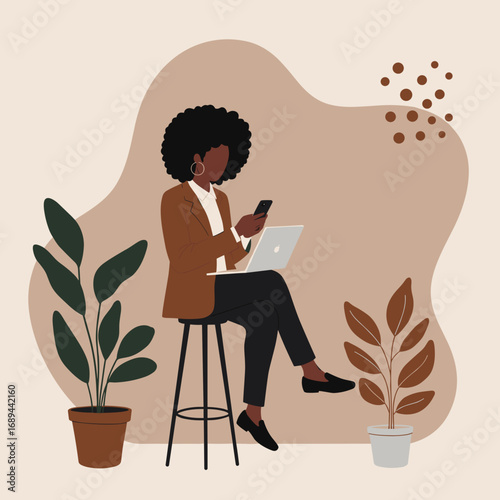 African American woman working with laptop and phone, embodying remote work, digital communication, and a contemporary business lifestyle.