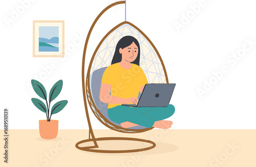 young woman sitting on a modern hanging egg chair  with cushions, indoors, comfortably working on a laptop