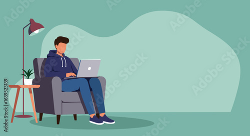 Casual young man engaged in work or study on his laptop from a comfortable armchair at home. Represents remote work, online learning, and a relaxed digital lifestyle.