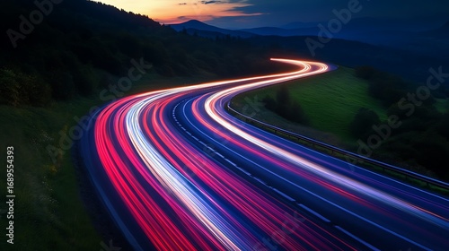 Winding mountain road at dusk with vibrant car light trails highway traffic photo