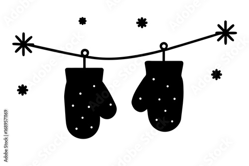 Pair of black mittens hanging on a clothesline with snowflakes