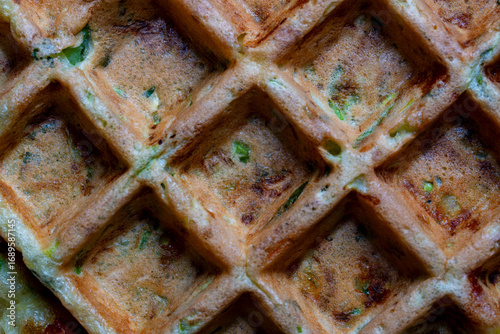 Background and texture of zucchini and herbs waffle made with waffle maker, closeup, top view. Tasty squash waffles for eat