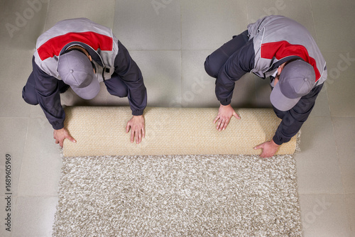 Fotografie Workers rolling Carpet On Floor At Home, view from above