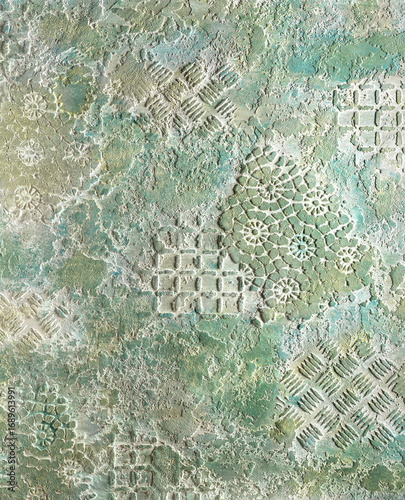 Textured wall surface featuring intricate patterns and designs in soft green and white tones, showcasing artistic craftsmanship and unique visual appeal for creative projects