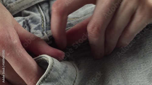 Close-up of woman's hands examining new jeans at home on a table, recorded with ambient sound.