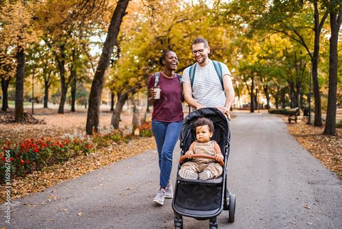 Foto Mixed race couple walks their son's stroller through the park