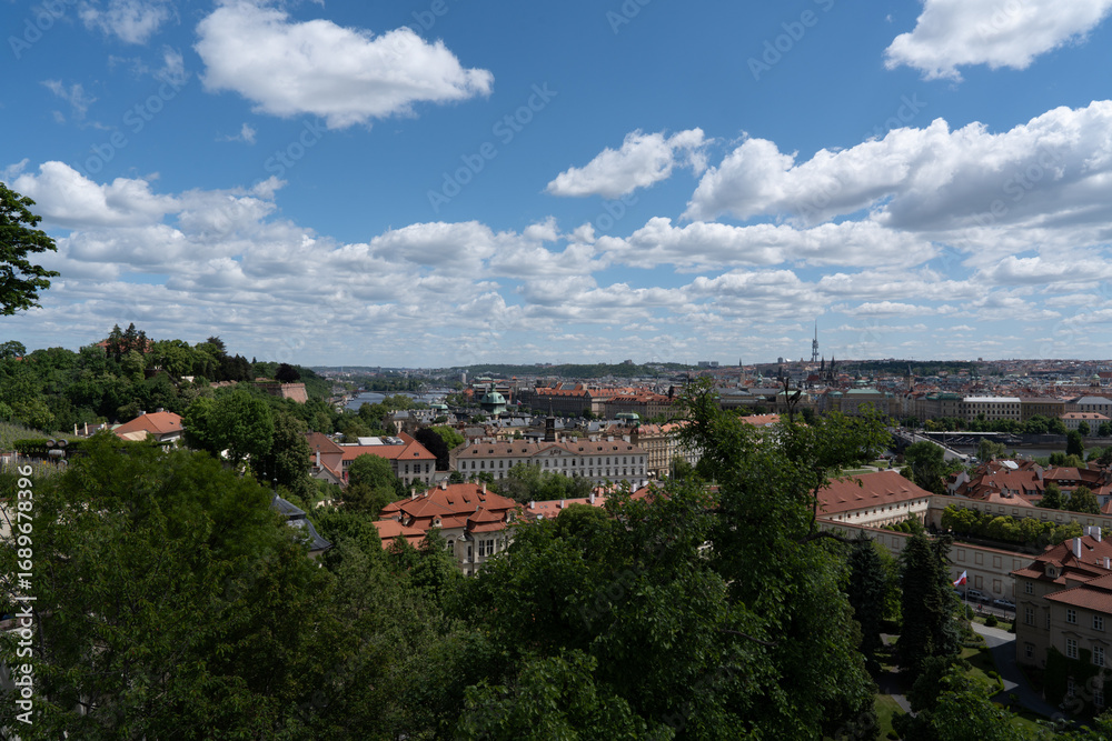 Fototapeta premium Scenic cityscape view on a sunny day with blue sky and clouds. Architecture and greenery dominate the horizon.