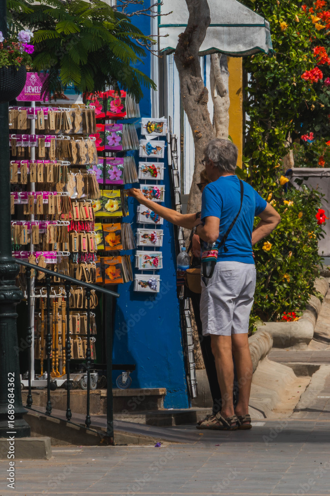 Naklejka premium Tourists choosing a souvenir on a colorful corner of Mogan