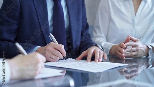 Business people wearing suits signing important documents during a corporate meeting. Win-win concept