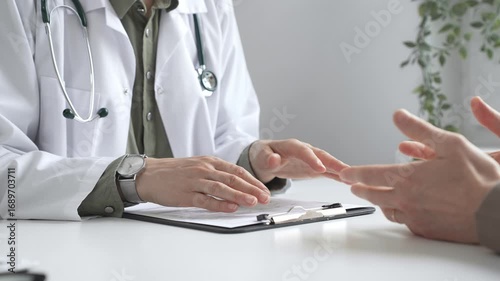 Doctor is explaining diagnosis to patient during a medical consultation in a medical office, gesturing with hands. Medicine and health care concept