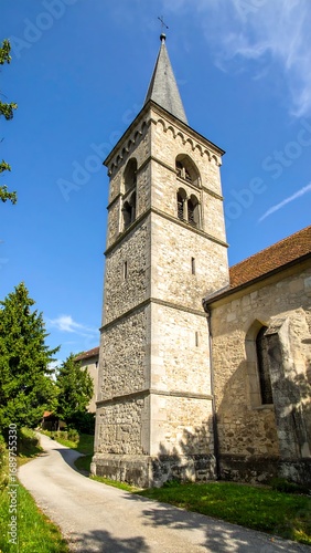 Historic church tower under blue sky in serene landscape