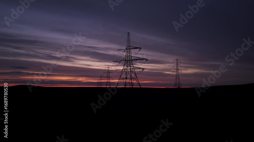 Silhouetted Power Transmission Pylons and Cables Against a Stunning Sunrise Sky in the Rural English Landscape
