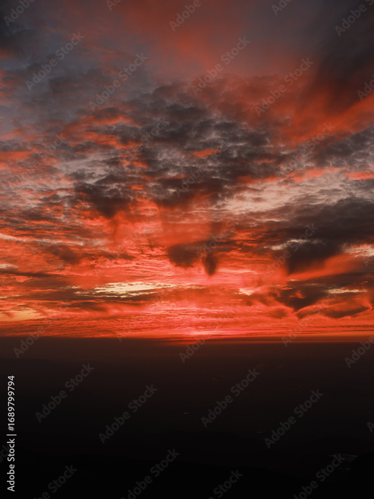 Fototapeta premium Dramatic Red Sunset Over Mountain Horizon with Vibrant Clouds